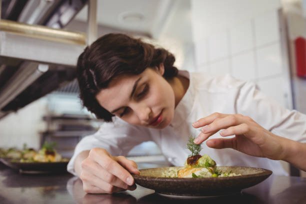 istock Female chef examining appetizer plate at order station 683434988