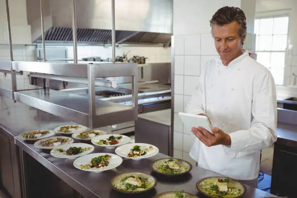 Photo of Male chef using digital tablet at order station