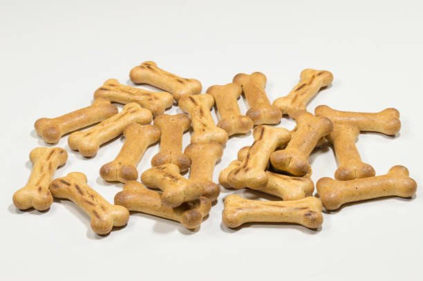 dog biscuits A pile of dog biscuits on a white background premio stock pictures, royalty-free photos & images