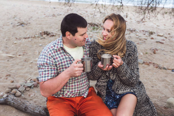 istock Happy couple drinking cocoa with marshmallows outdoors at the beach 683441464