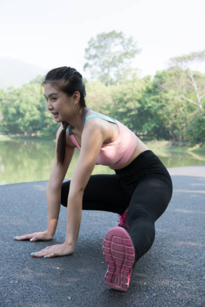 istock Female sport fitness runner getting ready for jogging outdoors on forest path in spring or summer. Healthy young asian woman stretching before running or after exercise in park. 683444668