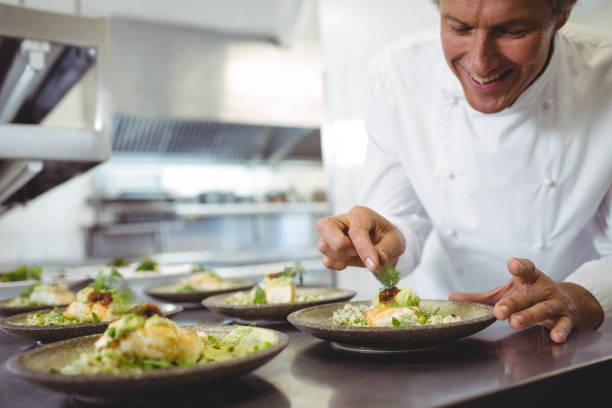 istock Male chef examining appetizer plates at order station 683448472