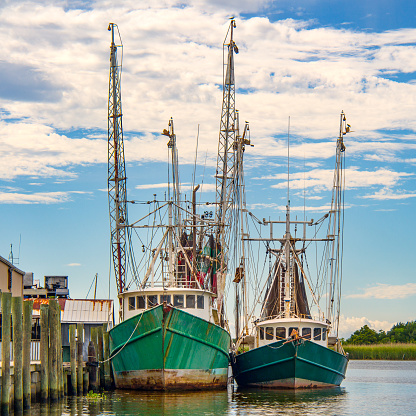 Two shrimp boats docked side by side along a river
