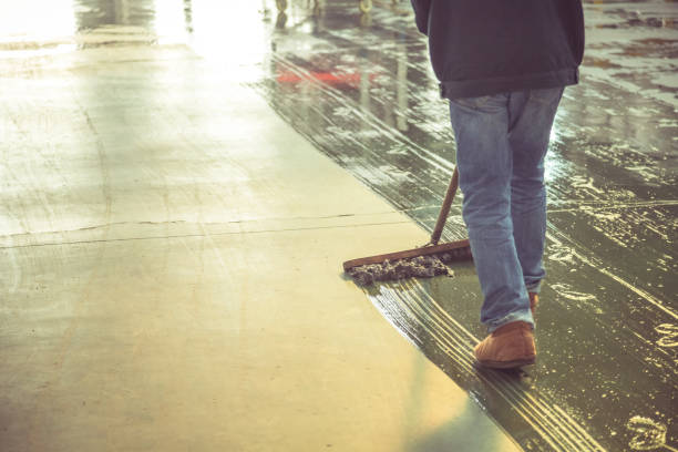low section of male worker mopping the concrete floor in factory stock photo