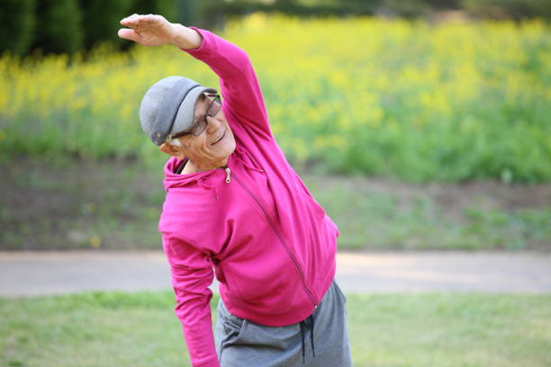 istock senior Japanese man in pink wear doing standing side bend exercise 683469324