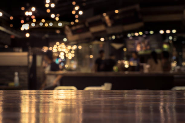 Wood table with blur light in night cafe,restaurant background Wood table top with reflect on blur of lighting in night cafe,restaurant background/selective focus.Wood table top with blur light bokeh in dark night cafe,restaurant background .Lifestyle and celebration concepts pub bar stock pictures, royalty-free photos & images