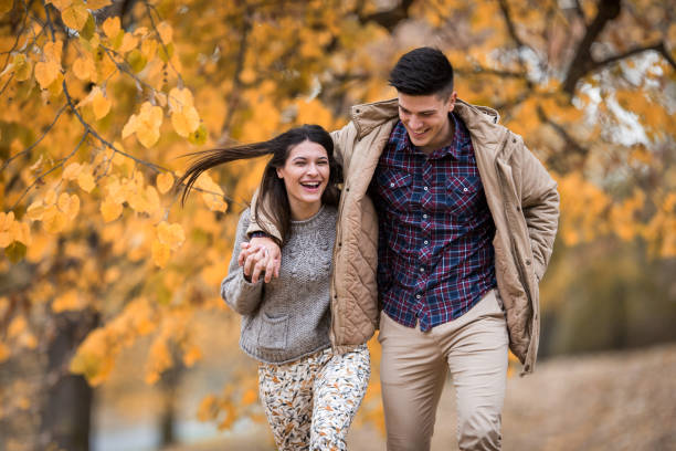 istock Young couple laughing while running embraced in nature. 683503826