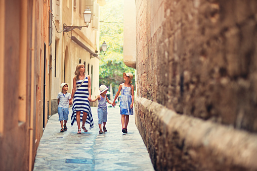 Mother with kids walking narrow street of old town of Palma de Mallorca, Spain
