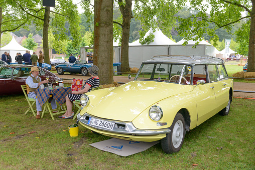 Citroen DS Break station wagon with people having a Picnic in a park during a beautiful summer day. The car is on display during 2016 Classic Days at Dyck castle near Juchen in Germany.