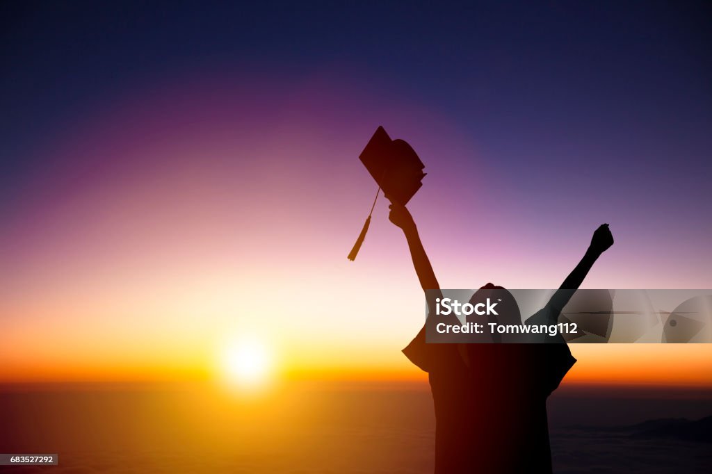 silueta del estudiante celebra graduación viendo la luz del sol - Foto de stock de Graduación libre de derechos