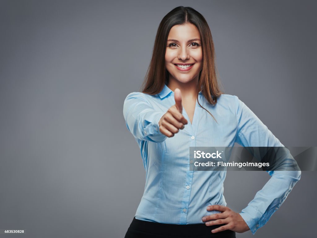 Enthusiastic approval! Confident young businesswoman giving the thumbs up against a gray background Thumbs Up Stock Photo