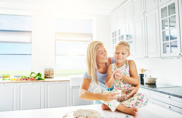 istock Girl sitting on kitchen counter beside mother 683533738