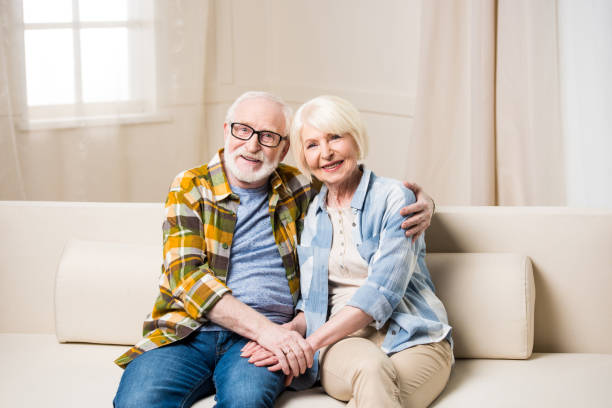 istock Happy senior couple sitting embracing on sofa and smiling at camera 683533848