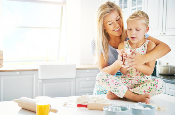 istock Little girl getting help to mash bread dough 683534096