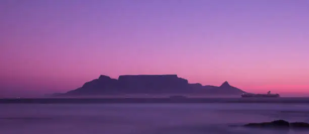 Table mountain in the distance from Blouberg beach as the sun goes down.