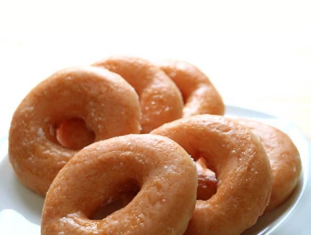 istock Closed up heap of sugar-glazed doughnuts served on white plate 683539474