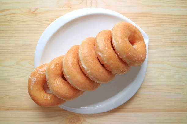 istock Top view of lined up sugar-glazed doughnuts served on white plate 683539560