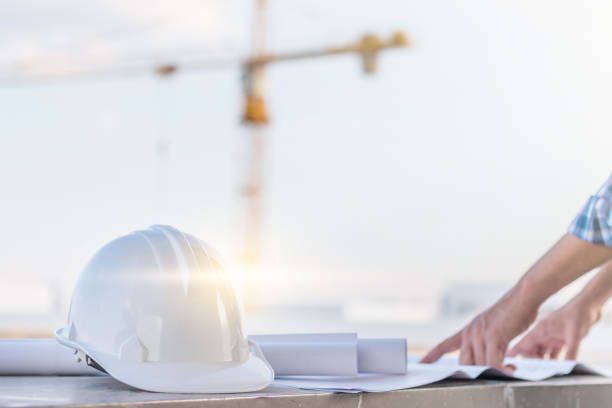 istock The white helmet and the man verify blueprint for his project with construction site and crane background 683548224