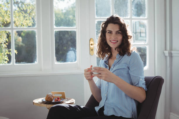 istock Smiling woman having cup of coffee at home 683553366