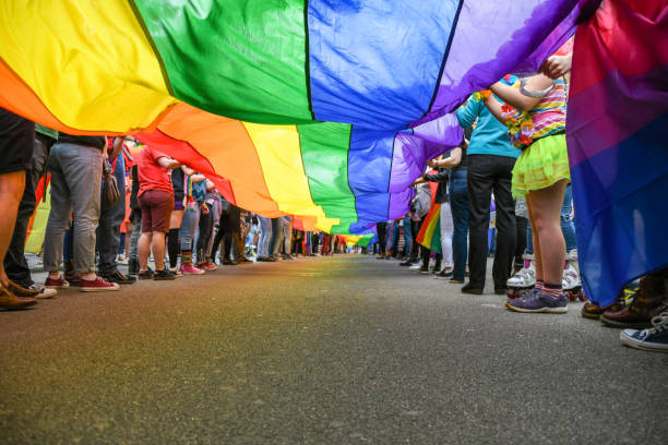 under a lgbt pride flag - gay pride flag fotos imagens e fotografias de stock