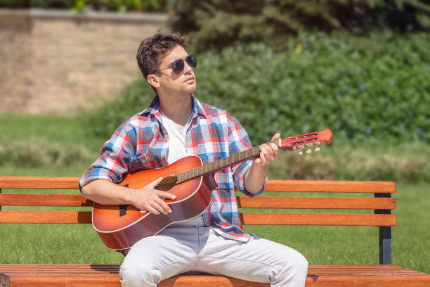 istock Young man playing acoustic guitar in the park 683560772