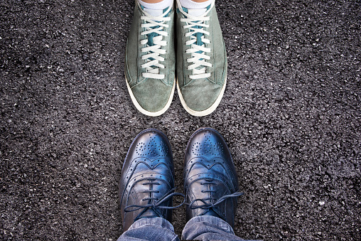 Sneakers and business shoes face to face on asphalt, work life balance concept