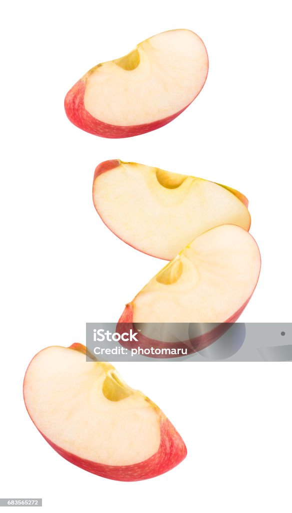 Isolated red apple pieces flying in the air Isolated flying apple wedges. Four falling pieces of red apple fruit isolated on white background with clipping path Apple - Fruit Stock Photo