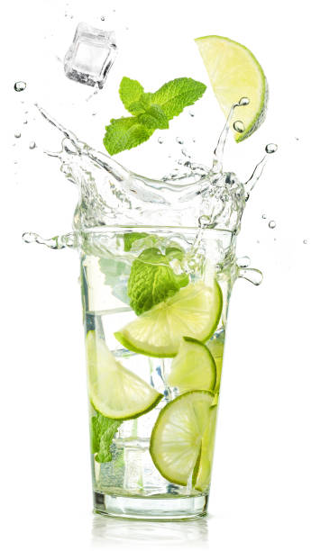 lime and mint falling into a mojito glass splashing - water with glass cocktail imagens e fotografias de stock