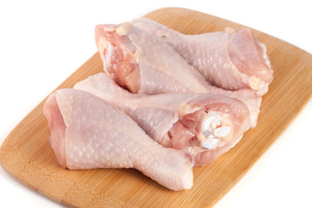 istock four raw chicken drumsticks on a wooden cutting boardn white background 683569166