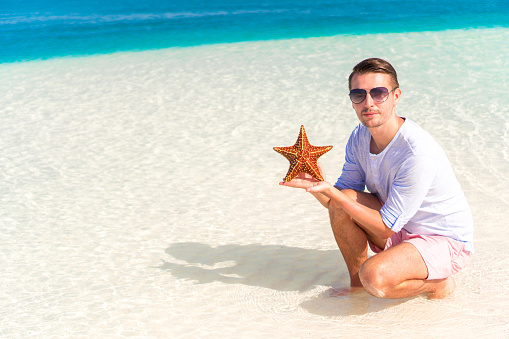 Caucasian man with starfish on the beach