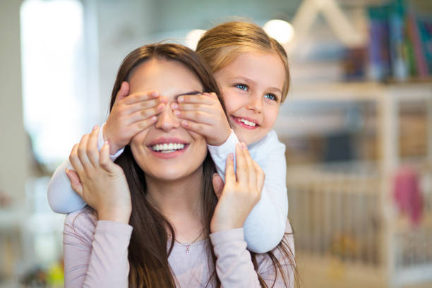 счастливая маленькая девочка покрывает глаза матери - family with one child domestic life caucasian love стоковые фото и изображения