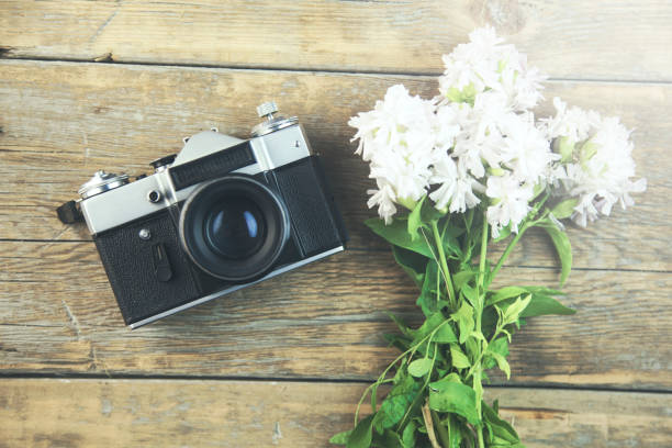 flowers and camera on wooden background