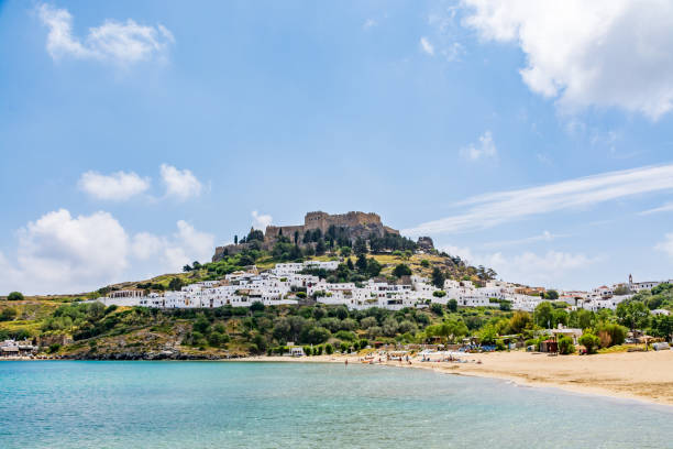 View of Lindos city, castle and Megali Paralia beach on a beautiful day, Rhodes island View of Lindos city, castle and Megali Paralia beach on a beautiful day, Rhodes island, Greece paralia stock pictures, royalty-free photos & images