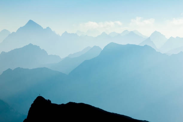 Spectacular blue and cyan mountain ranges silhouettes. Summit crosses visible. stock photo
