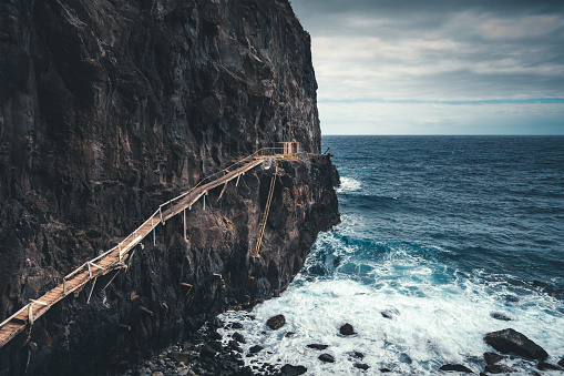 View on a large cliff with spectacular wooden path used by fishermen (Madeira Island).