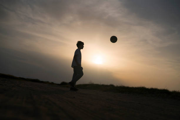 istock Boy playing football at sunset 683652632