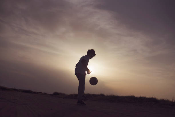 istock Boy playing football at sunset 683652646