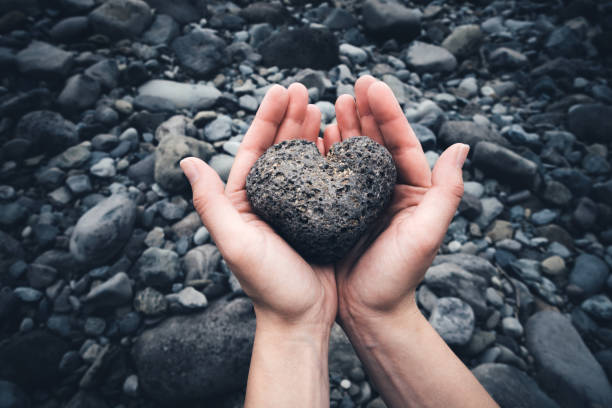 Woman holding heart shaped stone in her hands.