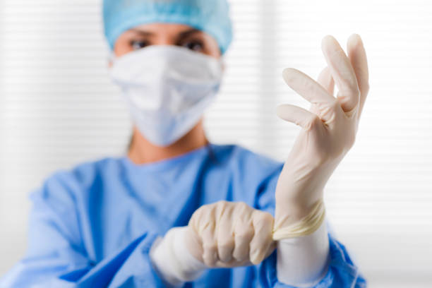 хирург-женщина, надевая хирургические перчатки - surgical scrub стоковые фото и изображения
