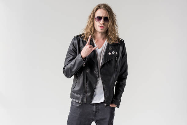 istock young handsome man in black leather jacket showing rock gesture isolated on grey 683658776
