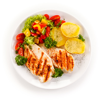 Grilled chicken breast and vegetables on white background