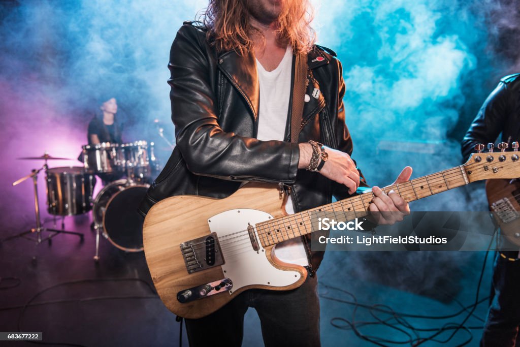 Cropped shot of electric guitar player playing hard rock music on stage Rock Group Stock Photo