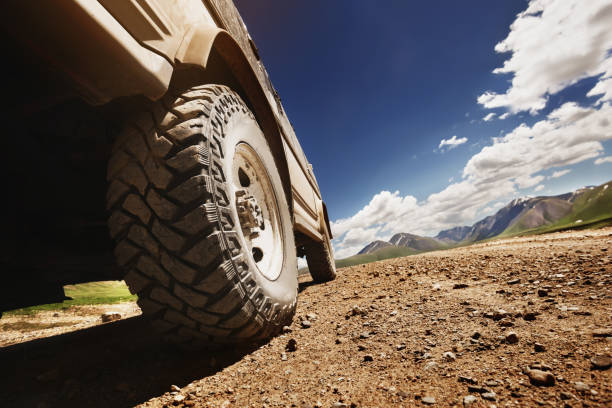 Big offroad car wheel on country road Bottom view to big offroad car wheel on country road and mountains backdrop. Space for text jeep off road stock pictures, royalty-free photos & images