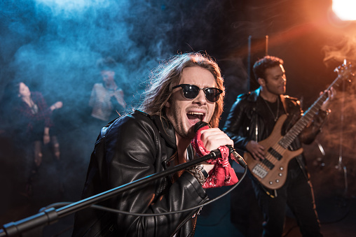 Cantante masculino con micrófono y rock and roll band interpretando música de rock duro en el escenario photo