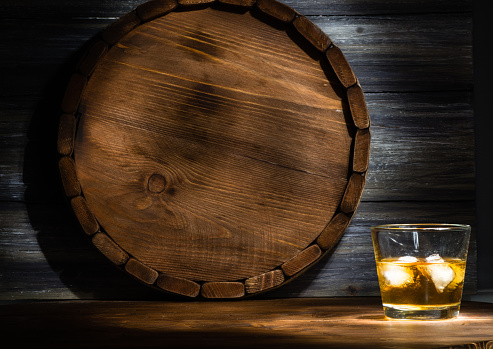 whiskey on a wooden background in the darkness, drawn by light and the barrel