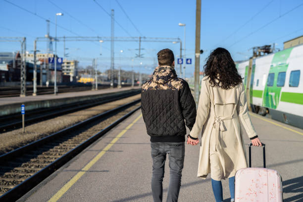 istock Rear view of young couple holding hands at train station platform 683706584