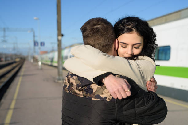 Young couple hugging at train station platform outdoors