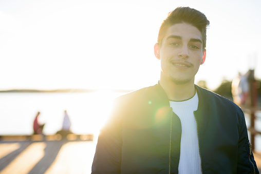 Young handsome man outdoors in nature with back lit sun and lens flare horizontal shot