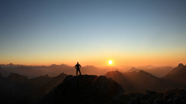 istock Man reaching summit enjoying freedom and looking towards mountains sunset. 683726254