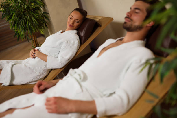 istock Couple in bathrobes relaxing in lounge chairs at spa 683739544